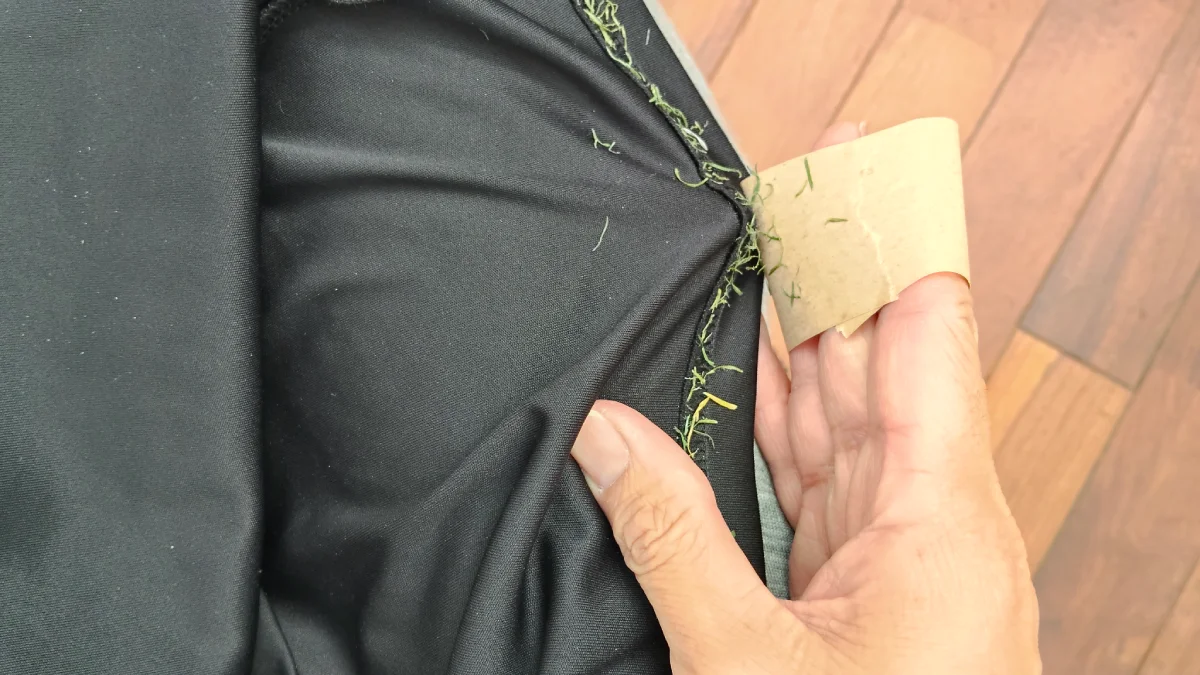 【途中１】練習着上の裾の縫い目の人工芝をテープで取ろうとする